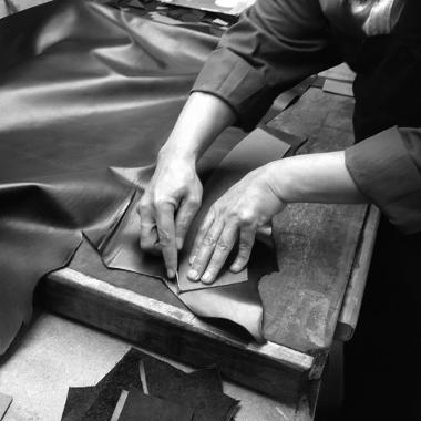 a person using a stencil to cut out a piece of leather on a workshop table 